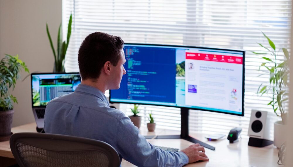 Photo by Luke Peters man in gray dress shirt sitting on chair in front of computer monitor