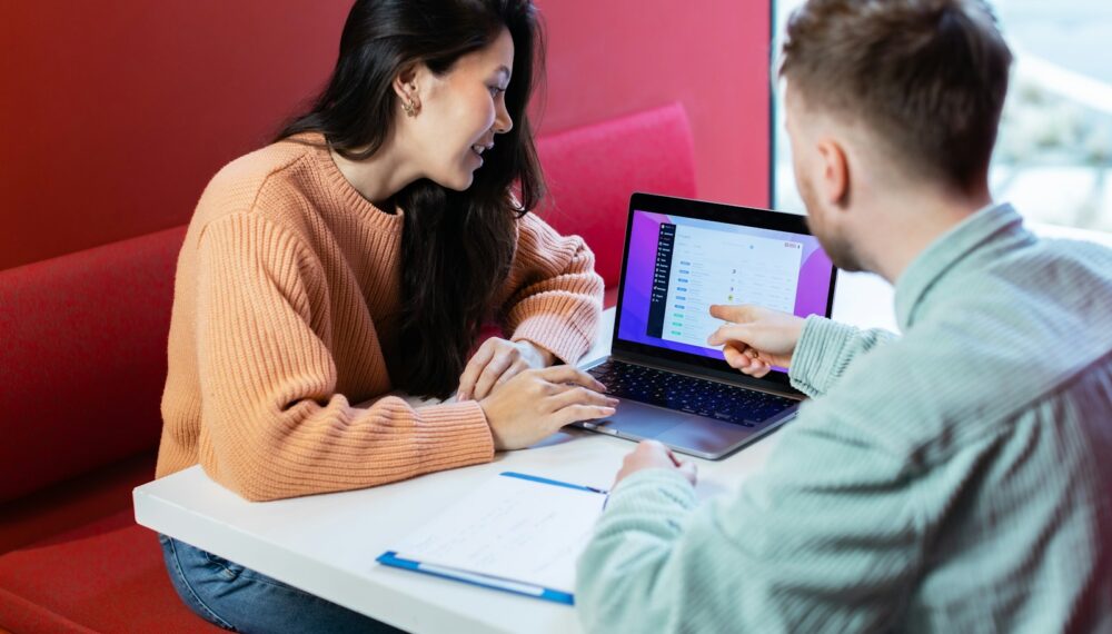 Photo by Rodeo Project Management Software a man and a woman sitting at a table with a laptop